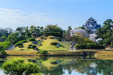 Japanese garden with large pond in the foreground and castle in the background