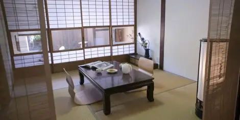 Dans le fond de la pièce, des shôji (portes coulissantes transparentes) séparent la pièce de vie du petit jardin extérieur.