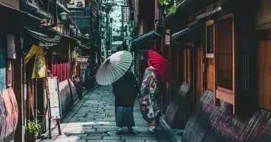 Pareja caminando por la calle sosteniendo paraguas en Kioto