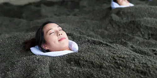 On the volcanic black sand beach of Beppu, you can enjoy a "sand bath" facing the sea